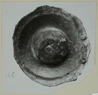 Corroded bronze disc-shaped mounting fragment with a central boss, photographed from above.