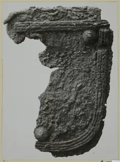 Corroded metal fragment with ribbed moulding and two rounded knobs