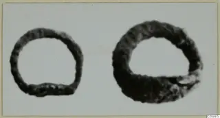 Two dark, corroded metal rings on a pale background, one smaller than the other.