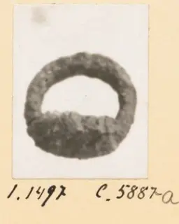 Corroded dark metal ring from Idalion, shown on a small mounted photograph