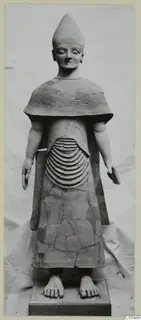 Terracotta statue of a standing figure in a tall conical hat and ridged cape, on a wooden base