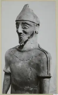 Terracotta statue of a bearded standing man in a tall pointed cap, shown from the chest up