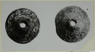 Two round disc-shaped objects with central holes, decorated with concentric rings and small circular motifs.
