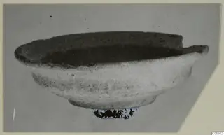 Plain pottery bowl with a rounded body and flaring rim, seen from the side.
