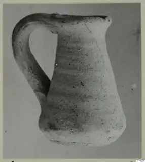 Plain white pottery jug with a loop handle, seen from the side