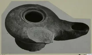 Terracotta oil lamp with a round filling hole and a long oval nozzle to the right.
