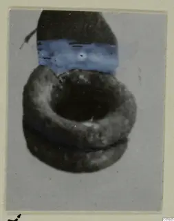 Silver earring, a ring-shaped object, photographed against a grey card mount.