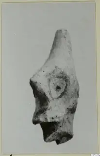 Terracotta figurine fragment with a tapering top, a raised rounded area on the face and a broken base.