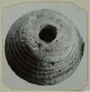 Rounded terracotta object with a large hole at the top and concentric ridges, seen from above
