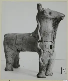 Terracotta figurine of a four-legged animal seen in profile, with a thin applied clay strip on its neck and body