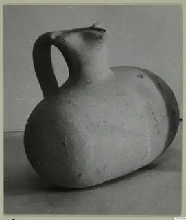 Pottery Plain White vessel with a tall strap handle and pinched spout, lying on its side