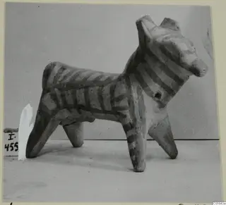 Terracotta figurine of a four-legged animal with dark painted stripes on its body and legs