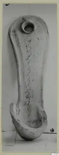 Pottery object from Idalion with a round hole at one end, a wavy incised line down its length and a curved, broken lower end