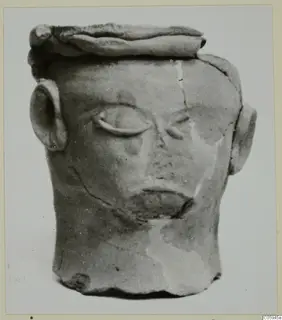 Terracotta head-shaped object from Ayia Irini, with relief eyes, mouth and ears, photographed on a card mount