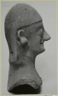 Terracotta head fragment in right profile, with a cap-like covering over the crown and a broken neck