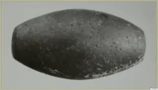 Elongated barrel-shaped bead from Idalion, dark grey with pale speckles.