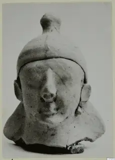 Terracotta bust of a man from Ayia Irini, shown frontally with a tall capped head and a prominent nose.