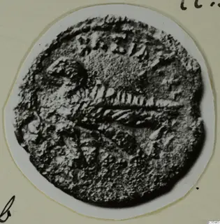Coin from Idalion with raised central design, shown enlarged on a white circular card mount