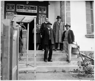 Group of six people posing on concrete steps in front of a building with an ornate iron-grilled doorway, Omologitades, Nicosia