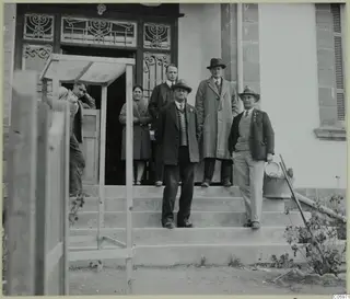 Group of six men and a woman posed on the steps of a building at Omologitades, Nicosia