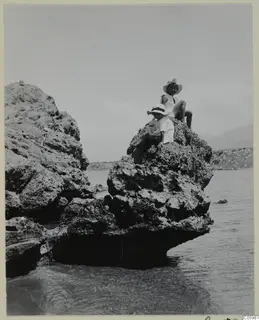 Two children sitting on a rocky outcrop above the sea at Kyrenia