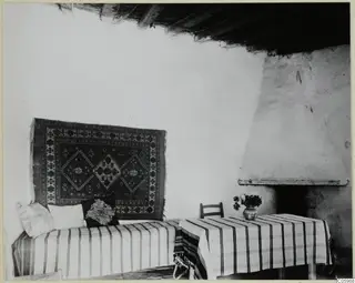 Interior with a striped sofa or bed, a hanging rug and a white fireplace at Machairas
