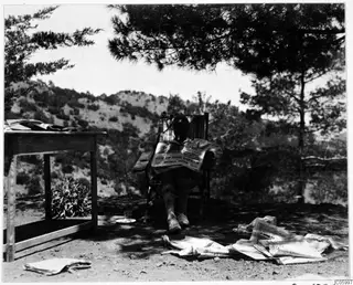 Einar Gjerstad reading newspapers outside the expedition house at Machairas