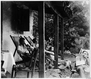 Three men resting on deck chairs on a terrace outside the expedition house at Machairas.