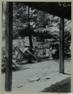 Man and woman resting in deck chairs on a terrace at Machairas, with a pine tree beside them