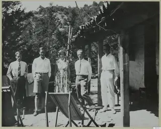 Five people standing in a row outside a whitewashed building with a wooden veranda at Machairas.
