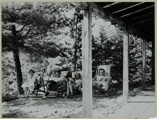Four people relaxing in striped deck chairs on a terrace under pine trees at Machairas.