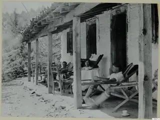 People resting in deck chairs on the terrace of a whitewashed house at Machairas.