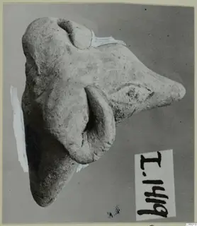 Terracotta minor plastic animal figurine on a grey backdrop, photographed sideways