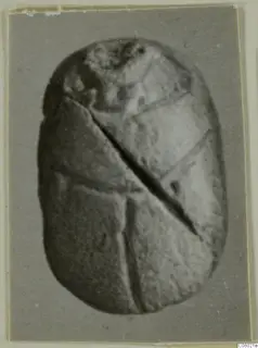 Oval scarab with straight incised lines and a dark diagonal groove across its face