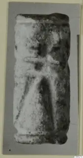 Cylinder seal standing upright, with a worn surface and faint incised lines.