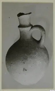 Small round-bodied jug with a tall neck and a loop handle, shown against a plain grey background.