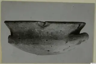 Pottery sherd of Grey Polished Ware from Idalion, shown in side view against a plain grey background