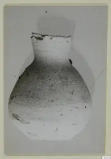 Pottery Plain White IV-V jug from Idalion with a broken rim, photographed against a grey background