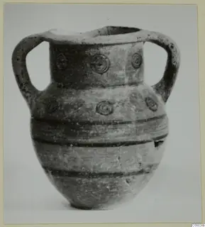 Two-handled pottery vessel with concentric circle motifs on the neck and shoulder and dark horizontal bands on the body.