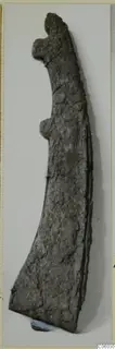Corroded iron tool from Idalion with a hooked upper end and a curved, widening blade