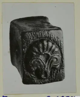 Bronze tools from Idalion: a dark block-shaped object with a raised fan-shaped motif on one face
