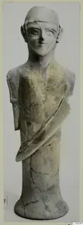 Terracotta statuette of a standing figure with a rounded head, repaired after breakage, photographed against a pale background.