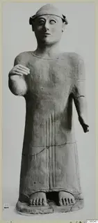 Terracotta standing figure in a long garment with one hand raised, from Ayia Irini