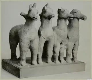 Four terracotta animal figurines standing in a row on a wooden base, Mersinaki