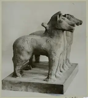 Terracotta group of three standing animals with pointed ears on a rectangular plinth, photographed from the front left.