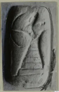 Rectangular glyptic object with a carved design, photographed close up in a grey tone