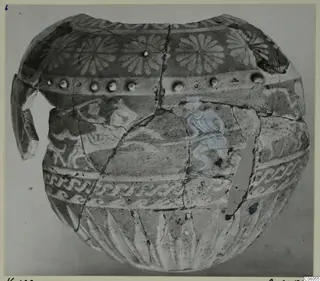 Faience jug, reconstructed from fragments, with painted rosettes, spiral bands and a blue-tinted motif