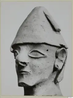 Terracotta head with a tall conical cap, large almond-shaped eye and prominent nose