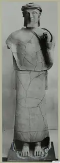 Terracotta statue of a standing bearded figure, Proto-Cypriote II, reassembled from fragments and shown on a dark plinth