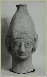 Terracotta head-shaped vessel with a tall neck rising from the crown, Ayia Irini, photographed against a plain background